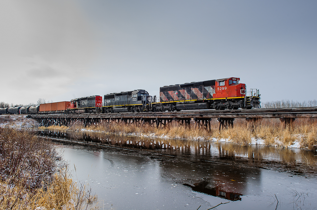 The morning fog has just began to dissipate as CN SD40-2W 5299, IC GP50r 3140 and CN SD40-2 5381 coast across a small wooden trestle on CN's Coronado Sub with Fort McMurray bound train L557 in tow.