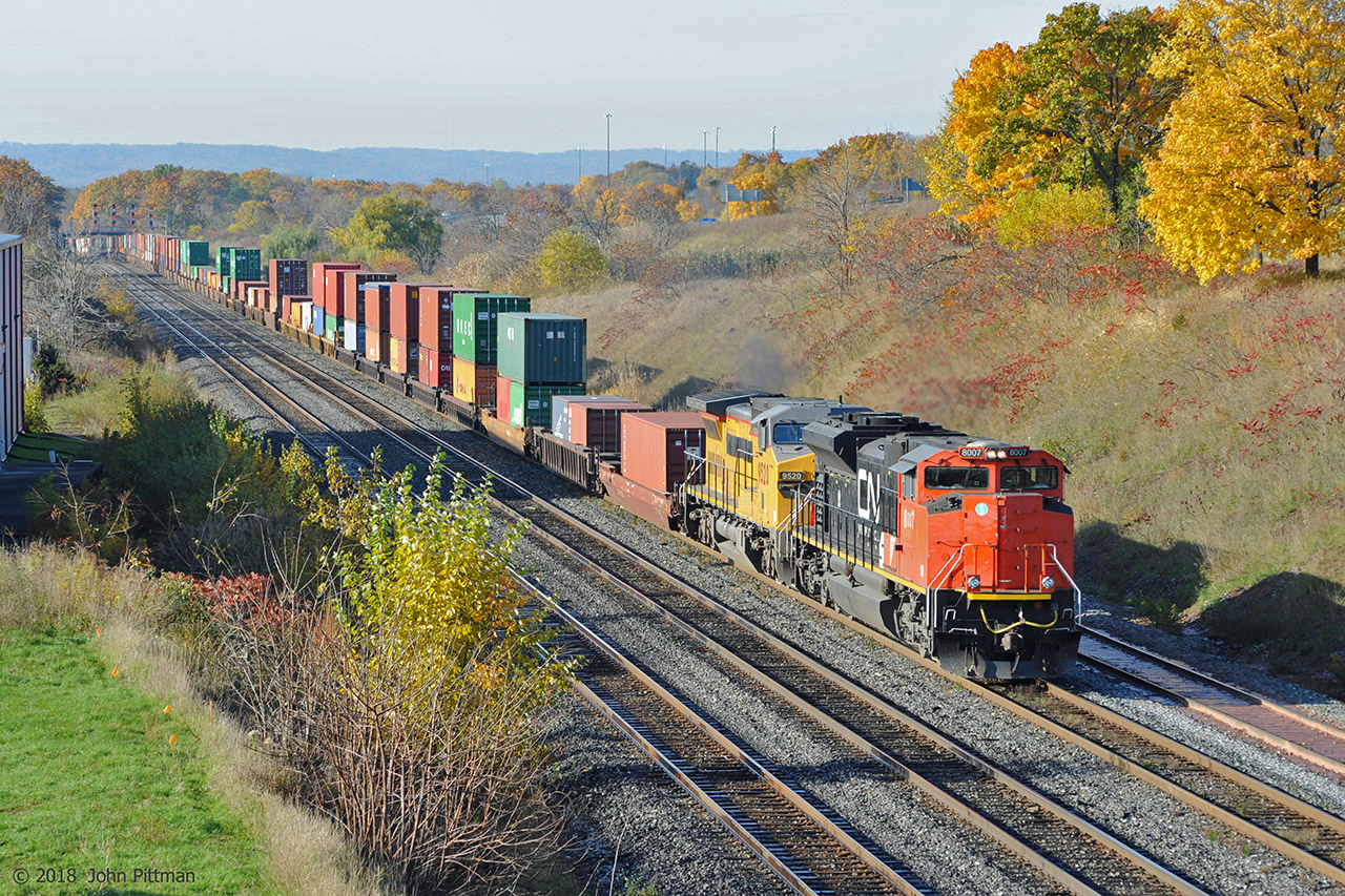 CN 8007 (SD70M-2) leads GECX 9520 (Dash 8-40CW, ex-UP 9520) at Oakville Sub MP 35.5 on a sunny autumn morning. They are powering eastbound intermodal train 148 up the grade from CN Bayview and CN Snake (signals in the distance).
"007" has lost its front CN logo, the cabside zeros are undersize, while the 7 is imperfectly painted - looks like a partial repaint of the orange-red on the cab.
GECX 9520 has a lot of black over-paint on the front - probably to cover a UP wings and shield emblem, or maybe it's a November moustache.  
Has anyone seen a GECX ex-UP unit which has/had the big US flag on the side? I wonder if there is any issue with over-painting that.