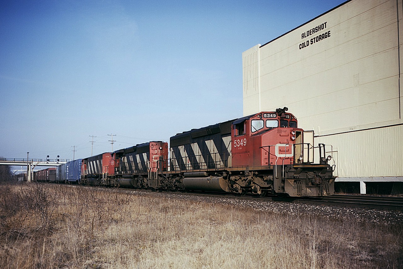 Dontcha Hate It When This Happens? Dept......I was feeling 'lucky' this nice early spring day. I set down the usual camera and switched to the good one.
Not bad, CN 5349, 5352 and one of those BBD units, 2118; which had a short life on CN; but I was very annoyed when I saw the front door was open. Well, these things happen.
Otherwise, a 'difference' scene. I am standing where since the new Aldershot leads have been constructed, the Cold Storage building is but a memory, as is the signal tower in front of the Waterdown Rd bridge. So, a lot of history here already
Beautiful day. Image was shot with Vericolor III 160 ISO sheet film in the old 4x5 Speed Graphic. Not cheap.