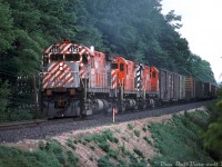 Three CP C424's muscle a westbound freight out of Galt, putting their 251's to work as they climb the grade known as Orr's Lake Hill between Galt and Orr's Lake. Both trailing units have been repainted into the then-current 8" stripe scheme, but lead unit 4243 is looking rather shabby in the old 5" striped Action Red livery, with its paint a mix of primer and sandblasted red in preparation for a repaint. This was likely one of the unpainted units that CP pressed into service during its Angus paint shop shutdown in 1978 (Steve Bradley mentions it in his photo <a href=http://www.railpictures.ca/?attachment_id=31972><b>here</b></a>), and it would eventually find its way into a proper coat of action red and 8" stripes. New ditch light mounts have also been installed in preparation for the addition of ditch lights, as CP was retrofitting them to its mainline power during that time in the late 70's.<br><br>CP favoured its 251-powered MLW fleet more than most, and after an early 80's rebuild program converting them to road switchers the C424 fleet (along with the RS18u units) went on to serve into the late 90's until retirement.<br><br><i>Bill McArthur photo, Dan Dell'Unto collection slide.</i>