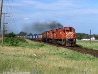 Hustling westbound for Toronto, three big MLW M's lead by M636 4712 head a CP freight (likely 507) with a healthy string of container-on-flatcar traffic on the head end, approaching Lawson Settlement Rd. east of Brighton. The blue CAST containers were a common sight on CP in the 1980's and 1990's on COFC flats, with the CAST Group being a major Eastern Canada/US-European container line. CP (through their CP Ships operation) would later buy CAST out of bankrupcy in 1995.<br><br><i>Keith Hansen photo, Dan Dell'Unto collection.</i>