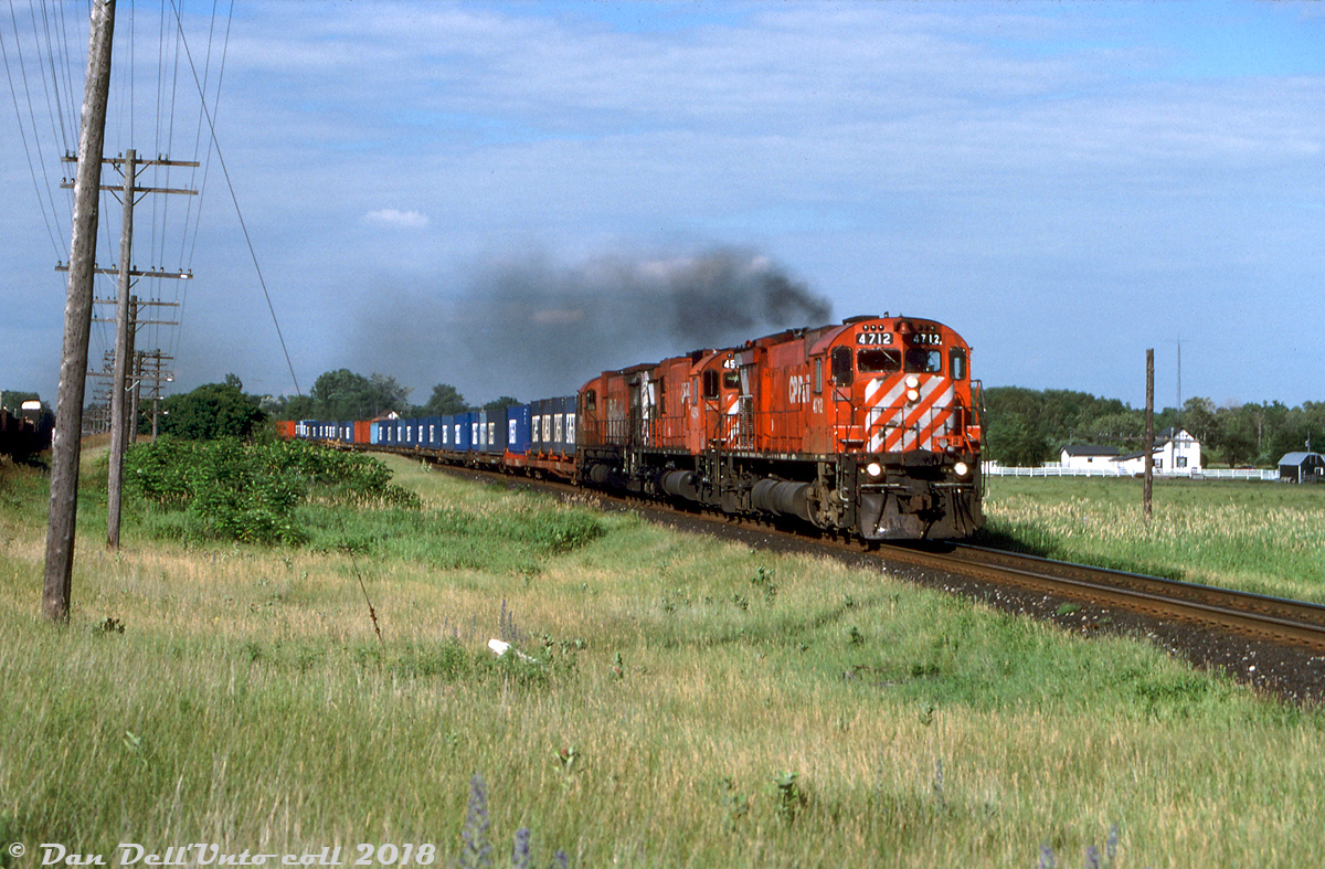 Hustling westbound for Toronto, three big MLW M's lead by M636 4712 head a CP freight with a healthy string of container-on-flatcar traffic on the head end, approaching Lawson Settlement Rd. east of Brighton. The blue CAST containers were a common sight on CP in the 1980's and 1990's on COFC flats, with the CAST Group being a major Eastern Canada/US-European container line. CP (through their CP Ships operation) would later buy CAST out of bankrupcy in 1995.
Keith Hansen photo, Dan Dell'Unto collection.