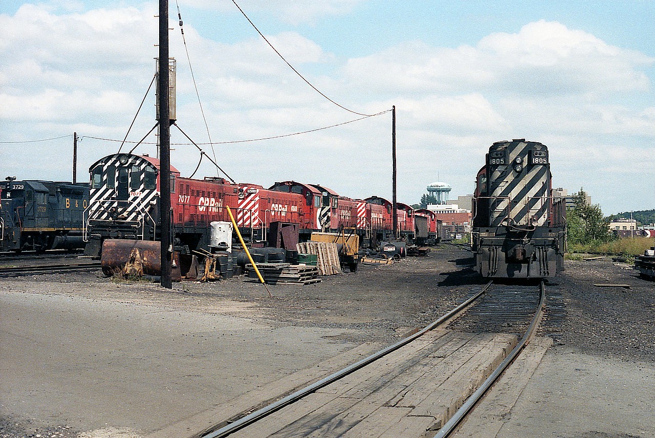 Interesting view of some old MLW switchers now stored and out of service. The closest unit to me, the 7077; in a few weeks departed for eventual display at Exporail in Quebec. It is of major disappointment now as I look back at this day and regret being told that 'my presence was not required' by yard personnel, which was a very polite way of telling me to 'get lost'.  As a result I did not get to record any other numbers save for the visible  6588 .........
Nice that the Sudbury watertower highlights the background, giving good ID to this image.

On the right are CP 1805 and 8775 in behind.