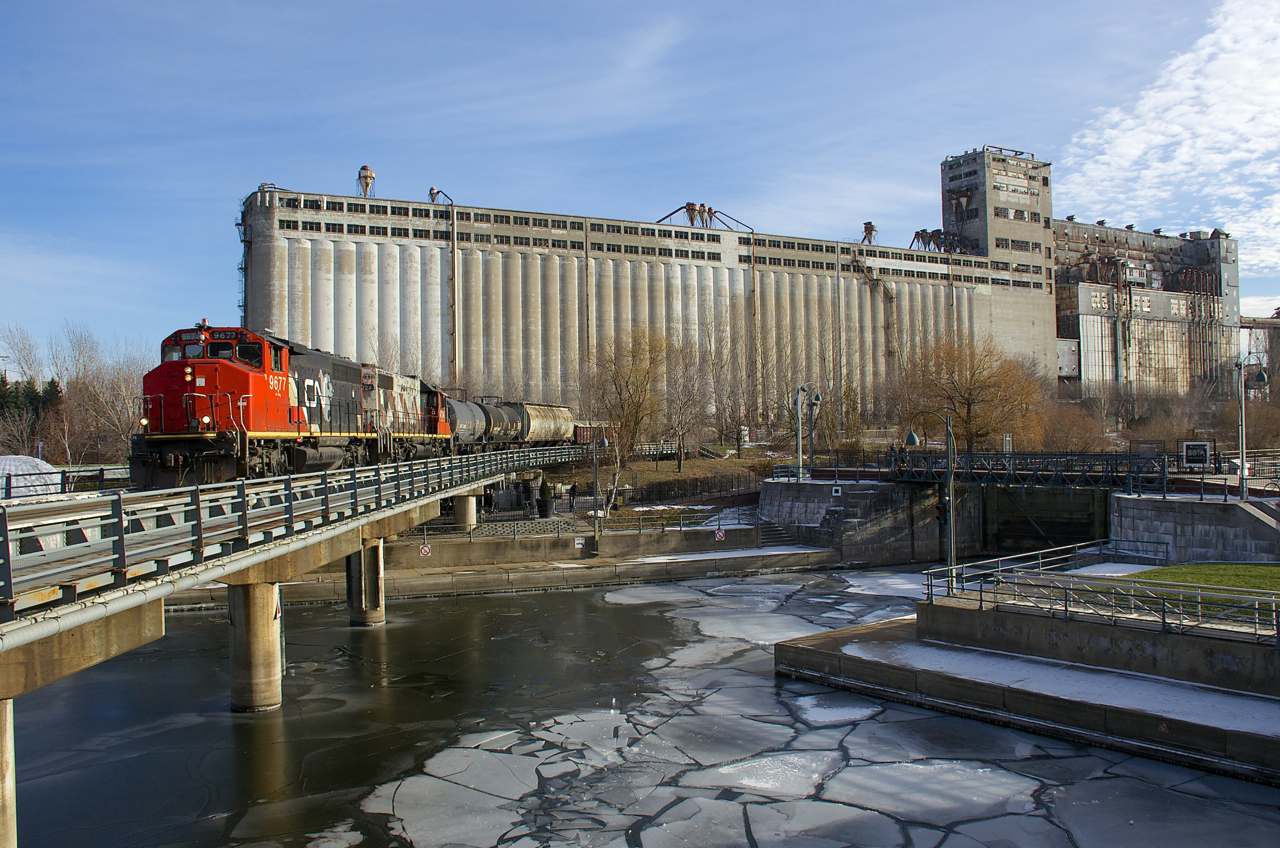 CN 9677 & CN 4724 have just 4 cars to interchange with the Port of Montreal as they pass grain elevator #5 and cross the partly frozen Lachine Canal.