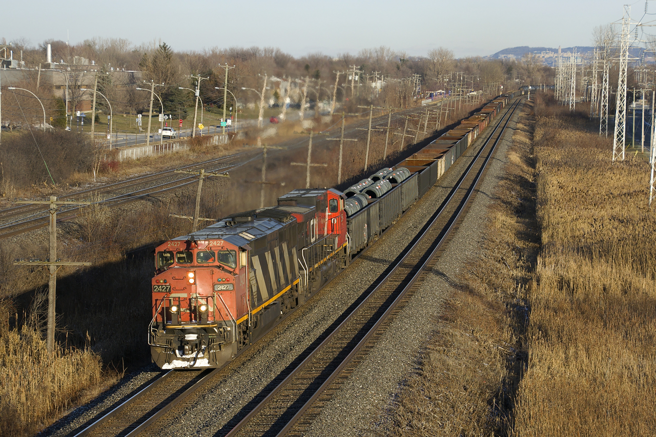 CN 2427 & CN 2554 lead a 75-car CN X321 westbound through Pointe-Claire on the Kingston Sub. The train is composed almost entirely of gons loaded with steel products, with about a dozen tank cars at the rear.