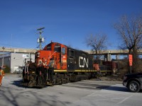 The Pointe St-Charles switcher with GP9 CN 7233, slug CN 227 and one boxcar (for the Kruger plant) is crossing Monk Boulevard as two crewmembers flag this rarely used crossing. The train is on the Turcot Holding Spur, which reopened around the start of the month after being closed since August, due to infrastructure and track work nearby. 