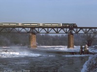 Operating in weekend VIA service to help handle the Christmas holiday crowds, a borrowed GO consist with GP40TC 506 leading a string of bilevel cars crosses the Grand River at Paris on VIA #70, heading eastbound on CN's Dundas Sub on a cold Saturday morning (if running on time it would have been around 8:44 - 9:00am, according to the timetable). According to other photos, this particular consist had a GP40TC at each end (500 and 506), sandwiching nine bilevels.
<br><br>
<i>Bill McArthur photo, Dan Dell'Unto collection slide.</i>