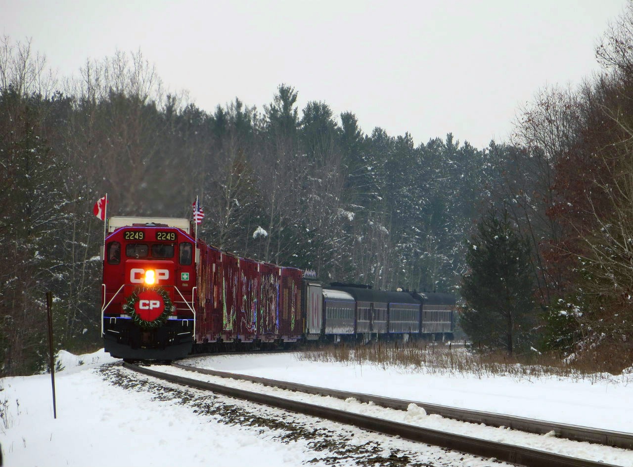 On a grey day, the Holiday Train comes out of the curve and is about to pass the Midhurst station sign.