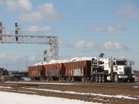 A CN/Brandt powered ballast train sits atop the bridge over Thickson road in Whitby. The work train will proceed just east of thickson road where an excavator will begin unloading the snow coloured ballast from the top of the cars. Work on the GO line here is part of the GO,s maintenance facility with new track and signals.  