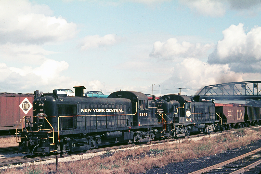 When was the last time you saw a pair of RS-3's on the transfer from Buffalo to Fort Erie?  For me, it was in Sept 1968 just west of the Central Avenue bridge which has been replaced with a concrete structure.  I am looking at the autos and think they might be 1969 Mercury Marquis Broughams. There is also a fallen flag on the Erie box car.