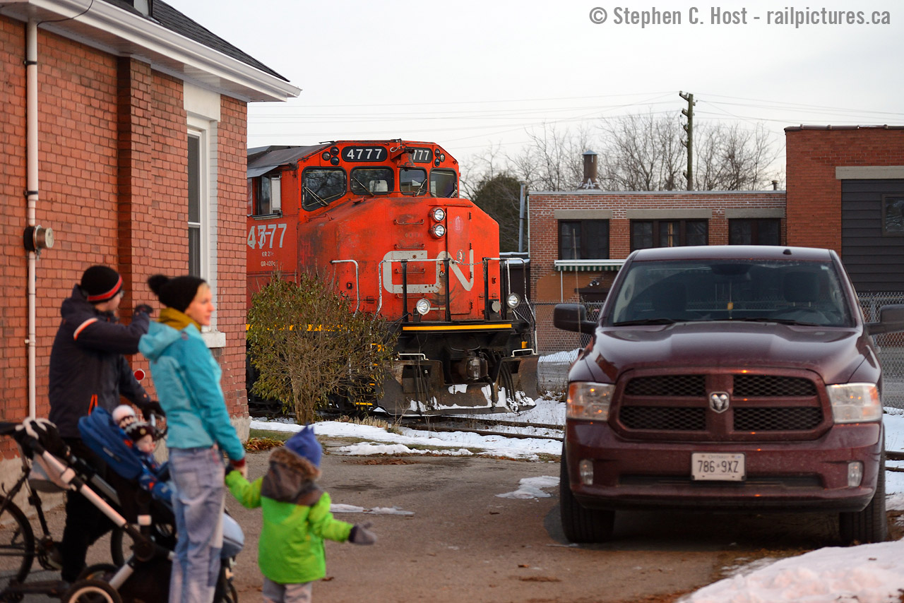 Peekaboo: A family marvels at the rare sight of a train along Crimea St in Guelph, 4777 plays peekaboo behind a house where the rails are mere feet to the cornerstone of the property. This track is the wye of the Guelph N Spur and has been like this for well over 70 years, the houses and factories dating to the 1940's at least if not older. This was taken across the tracks and behind  Kevin Flood's shot  taken a couple days earlier.