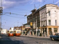 A classic scene in "The Junction": TTC PCC streetcars 4393 heading westbound and 4352 heading eastbound meet on Dundas Street West at the intersection of Keele Street, operating on the Dundas streetcar route that ran north past Dundas West subway station, up its namesake street and west to Runnymede Loop near the CPR West Toronto/Lambton yards. Signage and marquees of the local shops include Bourbon & Burgess Barristers, Tots n' Teens Shoes, Abel's Flowers, Stuart Mercer Real Estate & Insurance, and various local delis, barber shops, restaurants, and loan & financing offices.<br><br>This portion of the Dundas streetcar was discontinued the following year when the route was cut back to terminate at the aforementioned Dundas West subway station, in conjunction with the opening of the west and east Bloor-Danforth subway extensions on May 11th 1968. The new 40 Junction trolleybus route replaced the streetcars here effective that day (the last day of regular streetcar operation to Runnymede Loop was May 10th, with the last car finishing its run in the early hours of May 11th). <br><br>While the rails and streetcars have been gone for decades many of the old buildings shown remain, albeit with different storefronts and tenants. Some are listed on the city's Heritage Register and have undergone restorations to their facades as gentrification continues in The Junction neighbourhood.<br><br><i>Robert D. McMann photo, Dan Dell'Unto collection.</i><br><br><i>*Personal note: the slide collector remembers trips in the 90's with his own father (who worked for CNCP Telecommunications/Unitel nearby) to the Four Seasons Natural Foods, once located at 2837 Dundas St. W. (where the Mercer Real Estate office is located in the photo) for root beer and muffins, so this location holds some personal significance.</i>