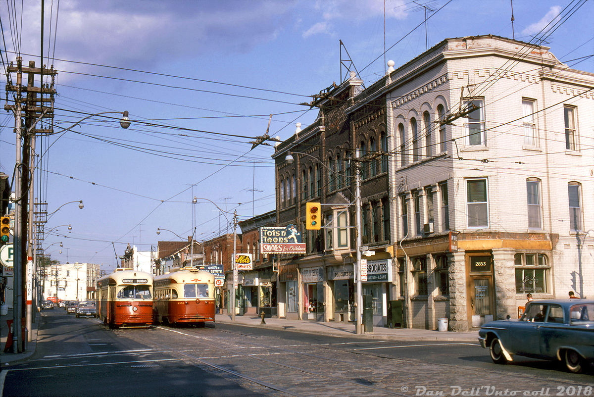 A classic scene in "The Junction": TTC PCC streetcars 4393 heading westbound and 4352 heading eastbound meet on Dundas Street West at the intersection of Keele Street, operating on the Dundas streetcar route that ran north past Dundas West subway station, up its namesake street and west to Runnymede Loop near the CPR West Toronto/Lambton yards. Signage and marquees of the local shops include Bourbon & Burgess Barristers, Tots n' Teens Shoes, Abel's Flowers, Stuart Mercer Real Estate & Insurance, and various local delis, barber shops, restaurants, and loan & financing offices.This portion of the Dundas streetcar was discontinued the following year when the route was cut back to terminate at the aforementioned Dundas West subway station, in conjunction with the opening of the west and east Bloor-Danforth subway extensions on May 11th 1968. The new 40 Junction trolleybus route replaced the streetcars here effective that day (the last day of regular streetcar operation to Runnymede Loop was May 10th, with the last car finishing its run in the early hours of May 11th). While the rails and streetcars have been gone for decades many of the old buildings shown remain, albeit with different storefronts and tenants. Some are listed on the city's Heritage Register and have undergone restorations to their facades as gentrification continues in The Junction neighbourhood.Robert D. McMann photo, Dan Dell'Unto collection.*Personal note: the slide collector remembers trips in the 90's with his own father (who worked for CNCP Telecommunications/Unitel nearby) to the Four Seasons Natural Foods, once located at 2837 Dundas St. W. (where the Mercer Real Estate office is located in the photo) for root beer and muffins, so this location holds some personal significance.