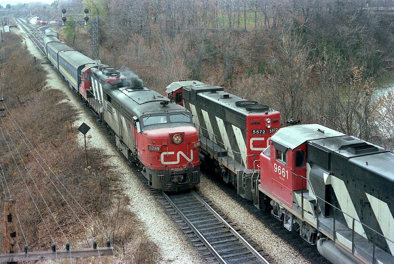 Westbound CN freight with CN 5572, 9661 and 9543 with 47 cars in tow is held by a redboard in order that eastbound passenger 'off the hill' with CN 6789 and 4104 clears. Early days of VIA, still lots of power in CN colours to be found. \Freight leader 5572 renumbered to 4772 in 1988. CN 6789 retired by 1989.