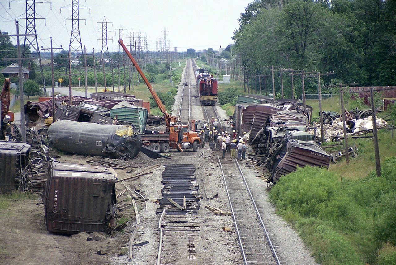 Bit of a mess here. I am on the Maple Av overpass looking east, and the crossing behind all this clutter at Nelles Rd.  On June 29th 1978 westbound #387, with 78 cars, jumped the tracks. A total of 29 cars derailed. The cleanup is progressing swiftly to get the line reopened.
I do not recall the cause of the derailment.