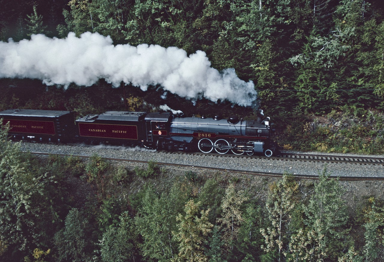 Having won the contract from CP to visually record the restoration and return to service of 2816 allowed the type of access to the Railway that I could previously only have dreamed of.        
We both chased and rode the 2816 between Vancouver and Calgary, and if the weather co-operated, had a chopper on standby for the section from Revelstoke to Golden.
Indeed the weather was on our side, and after chasing 2816 from Revelstoke to Glacier by truck, I switched places and boarded the chopper for the airborne chase from Glacier to Golden.  
This shot finds 2816 approaching the west switch of Stoney Creek