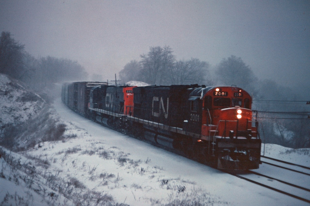 In a raging snow storm, CN C630m units 2001 and 2008 lead a westbound freight under the Plains Road bridge and into Bayview. Note the location of the horns and behind the cab on the engineer's side; the 2001 and 2000 were also the only CN C630m units with delivered with dynamic brakes.