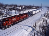 In the early days, CP's "Expressway" service ran behind GP38-2 units with "Iron Highway" technology. Snow kicked up by the westbound train hides the Beaconsfield commuter station as the train passes under the bridge near Beaconsfield High School on a cold January day.