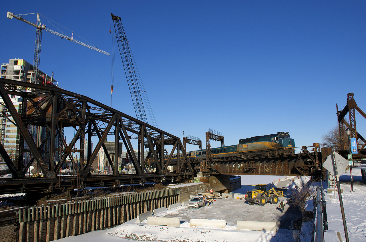 Preparatory work for the REM (Réseau express métropolitain) light rail project has begun where it will parallel CN's St-Hyacinthe Sub. Here VIA 67 with VIA 6413 leading crosses the Lachine Canal, with work ongoing underneath.