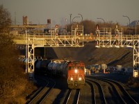 CN 323 is passing underneath a set of signals in Montreal West 25 minutes before sunset, with CN 2509, CN 8886, CN 2565 & 81 cars received in interchange from the NECR in St. Albans, VT.