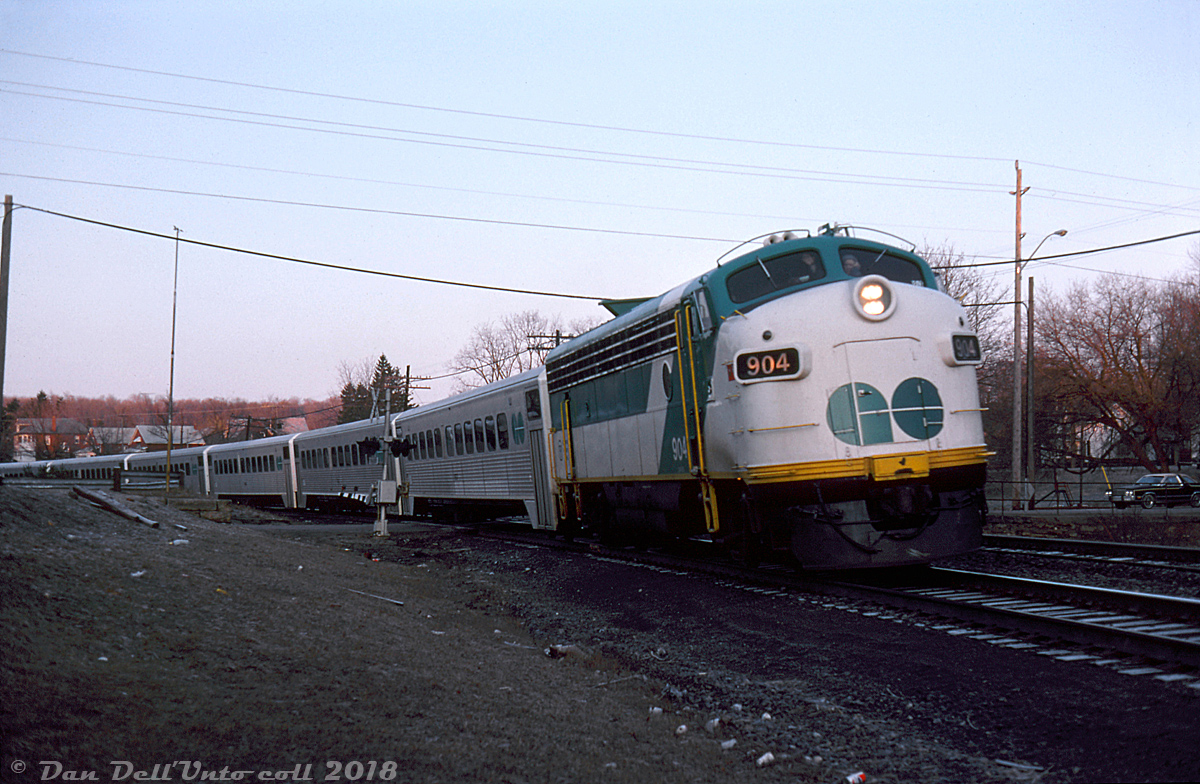 With a wave from one of the head-end crew, GO Transit APCU 904 (former Ontario Northland FP7 1513 rebuilt as a cab car/HEP generator) rounds the bend leading a string of single level Hawker Siddeley coaches and GP40-2W 703 through Campbellville at daybreak, deadheading with Milton line train #350 from the Guelph Jct layover yard to Milton Station. Given the train involved, this shot was likely taken sometime just after 6am as #350 was the first morning Milton line train of the day. According to the timetable schedule, upon arrival at Milton Station and taking on passengers, #350 would depart at 6:30am and after making stops along the line eventually arrive at Union Station in Toronto at 7:35am.The GO Milton line had come into existance only a few months before in October 1981 as an effort to expand service to the growing Halton & Peel suburbs along Highway 401, and also to offer a closer alternative to commuters in those areas than driving down to the Lakeshore West line. The Milton line started out as a rush-hour commuter service into Toronto in the mornings (trains #350, 352 & 354) and out in the evenings (#351, 353 & 355). Not much has really changed due to CP's ownership of the tracks, except having a few more rush-hour trains and extra station stops added on the line. GO now runs buses off-peak, and has been adding extra bilevels to its trains in a effort to increase capacity (the Milton line was the first to get L12's back in 2008).Reg Button photo, Dan Dell'Unto collection.