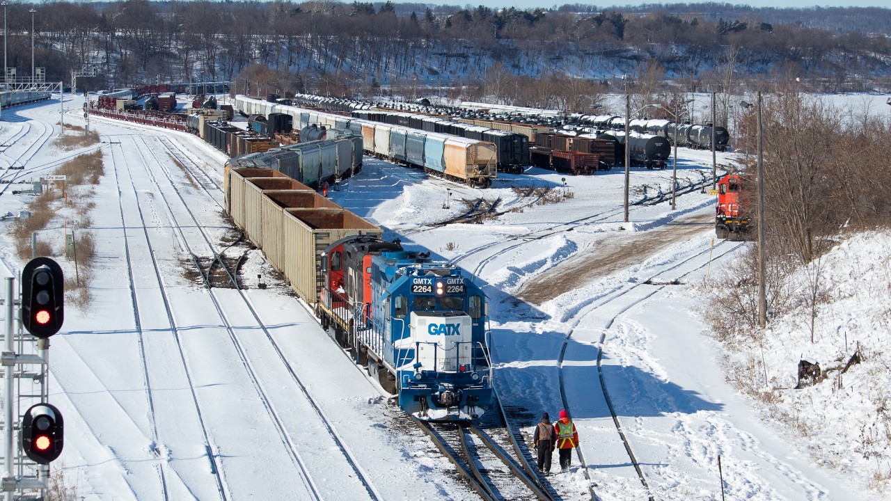 A look at Stuart Street post-CN resuming operations here. At bottom, a couple of crew members work the remote operated power outside in the bitter cold (-20C wind chill) as they switch the yard in preparation for the imminent arrival of 422 and later 331, both of which had work to do at Stuart. The switches in the yard have been cleared by crews working through the night and well into the day, after Hamilton got dumped on with over 20cm of snow. Compared with this shot in October 2018 when SOR was switching the yard and serving the industrial customers, the yard seems much more spacious now with more room on the ladder tracks, and has looked the way for much of the time that has followed the CN takeover. The long string of hoppers (where the second from the front is blue) are Nova Chemicals hoppers which have been sitting in the yard for several weeks now; something I can't say I ever observed in the past. These hoppers are commonplace on 330/331 (for OxyVinyls east of Port Rob I believe - perhaps someone can confirm), and sometimes on 421/422 as well.