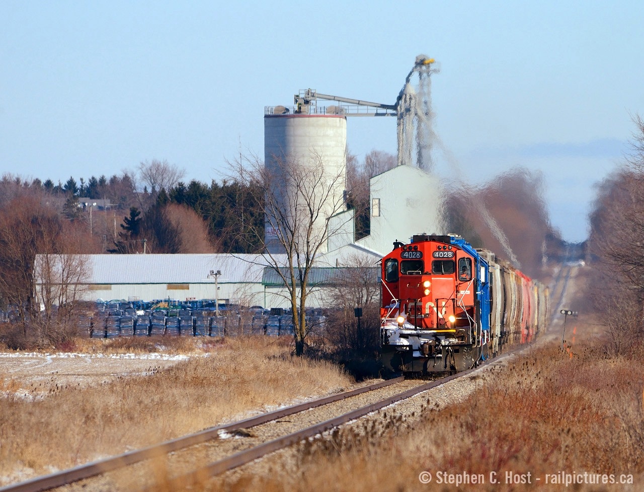 The Guelph subdivision can easily be described as a roller coaster, and this telephoto shot really shows it off well. CN L568 is at track speed of 55 MPH as they rush toward Stratford with 17 loads of fertilizer. From Kitchener to Highway 7, the Guelph sub can be described as a turkey trail (25 mph) but after HWY 7 and in the straight to Stratford, they are a rocket and chasing is impossible - you only get one chance. The customer in the background is apparently two customers, Shakespeare Mills Inc. and Quality Fertilizers Inc., both are active. I wish I did this shot in the GEXR days, but it's too late. With thanks to friend (and one time mod of this site!) Kyle Stefanovic for the inspiration.