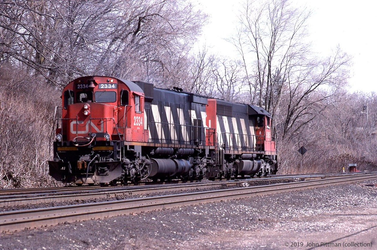 CN 5185 (SD40) and CN 2334 (M636 "Big Alco") are running light at mileage 0 on the north track of the Dundas Sub, where it joins the Oakville Sub at CN Bayview.  CN 2334 appears to have white class lights and headlights on, but the ditch lights don't seem to be, and the cab of CN 5185 is visibly occupied. Looks to me like the engines are eastbound with CN 5185 leading.