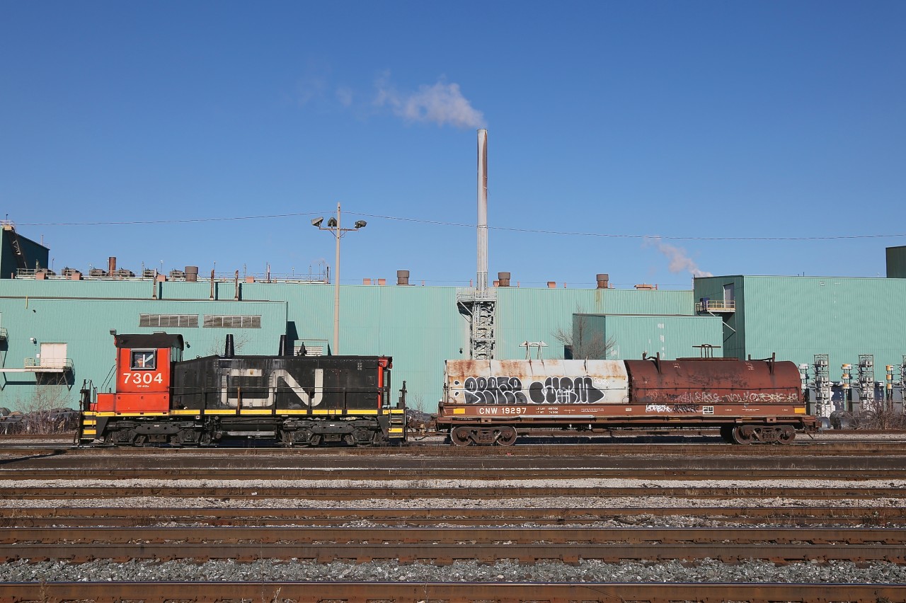 CN 7304 is seen working Parkdale Yard in Hamilton with Dofasco Central Shipping in the background.