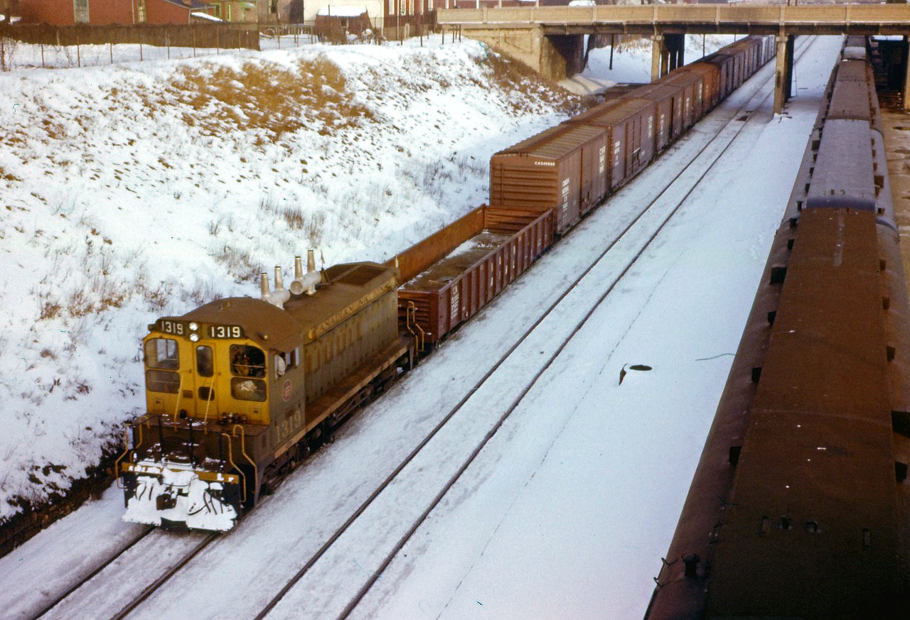 On a winter's day in early 1962, SW1200RS 1319 leads a wayfreight past commuter coaches at the Hamilton station towards Stuart Street yard.