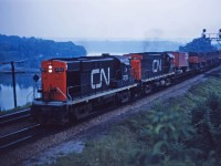 At dusk, CN RS18 3712 and C424 3214 lead piggyback train 252 through Bayview at the start of its trip to Montreal. Note the container flats with Dofasco steel several cars back.