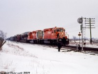 A drab winter's day is brightened up by a pair of shiny new SD40-2's, CP 5572 and 5574, working an westbound freight coming out of the west siding switch at Nissouri onto the Galt Sub, presumably after a meet with an eastbound. The white flags and class lights suggest this is an extra that would take the siding for higher class freights during meets, despite westbound being the superior direction. A cut of open autoracks full of new pickups and autos follow at the head end, and switch brooms stand at the ready in case the crew needs to sweep snow clear from the switchpoints. The Mile 104.9 marker plate on the signal suggests this is just east of Purple Hill Road., before the siding was extended westward at a later date (expanded from 6350 feet to 10150 feet, sometime in the 90's or 00's).<br><br>At the time this photo was taken, CP was taking delivery of its first order of the new and improved "Dash Two" SD40-2 model, and the Dean & Hanna CPR book lists both 5572 and 5574 as outshopped from nearby GMD London and added to the roster on the same date: February 26th 1972 (the 6th and 7th SD40-2's received). So even if this shot of both working together wasn't their maiden run, it couldn't have been taken too long after (the slide is dated March 1972). Ironically, both were retired at the same time (in September 2004) and sent via NRE to work in Brazil, becoming América Latina Logística 9457 and Ferrovia Centro Atlantico 4815 respectively. A warm retirement career and a long way from the frigid Ontario winters they started working in.<br><br><i>Gord Taylor photo, Dan Dell'Unto collection slide</i>