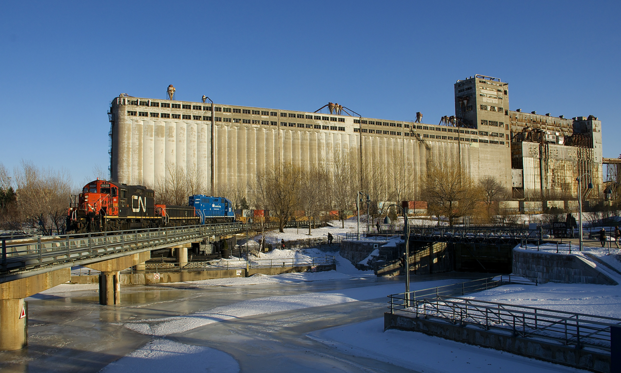 The Pointe St-Charles Switcher with CN 7233, CN 227 and GMTX 2257 for power is entering the Port of Montreal about an hour before sunset with 2,500 feet of containers. It is passing the massive but out of use grain elevator #5.