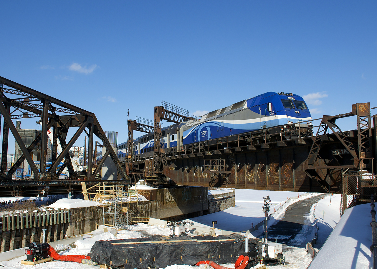 AMT 1352 pushes a deadhead move towards Central Station a bit before the afternoon rush hour. Work continues to progress on the REM light rail project (which will parallel the tracks here), with what might be a pillar going up in the Lachine Canal, which will certainly affect this angle.