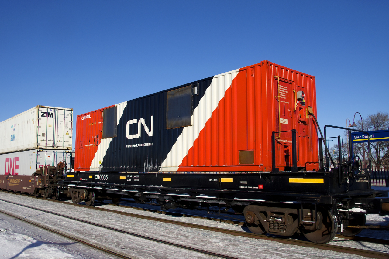 Distributed braking container CN 0005 is helping CN X106 maintain its air as it heads east through Dorval, its journey nearly over. CN has a number of these, as well as distributed braking cars built from boxcars.