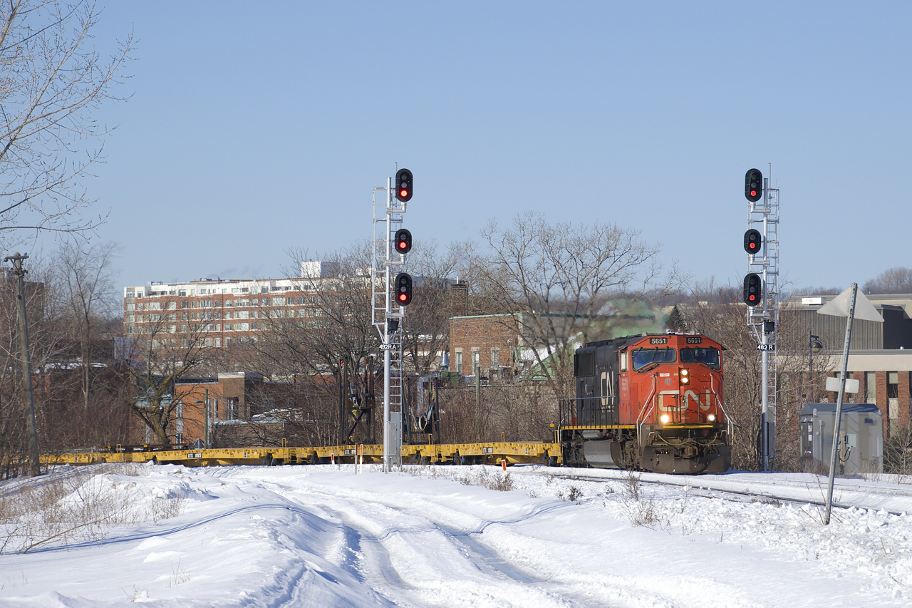 CN X312 (operating as CN 310, as the crew was called for CN 310 and X312 will be combined with 310 at Southwark Yard a bit further ahead) rounds a curve in St-Henri, with CN 5651 solo and empty flats headed to the Gaspé Peninsula for another load of windmill blades.