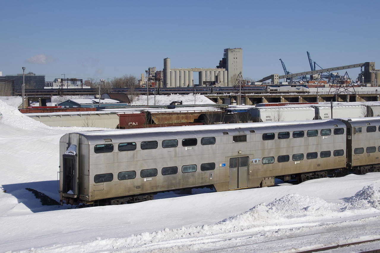 With stored gallery car AMT 926 at ground level in Pointe St-Charles Maintenance Centre, the Adirondack is leaviing Montreal on the high level St-Hyacinthe Sub with AMTK 2 and five Amfleet cars.