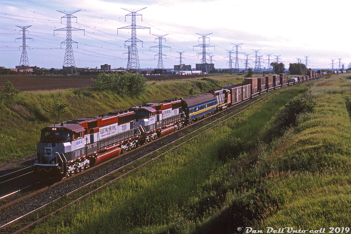 EMD demonstrator SD70M units 7001 and 7000 team up with a CN test car and GP40-2LW 9426, departing MacMillan Yard on train #208 onto the York Sub in the evening at Keele St. overpass. The two demos are showing off the latest and greatest of EMD's newly developed 70-series to CN. At this point, CN's most recent 6-axle mainline power purchases were the "Draper Taper" 5500-series SD60F's in 1989, followed by the two groups of 2400-series C40-8M's in 1990 and late 1992.

While CN would purchase 23 C44-9WL's from competitor GE the next year in 1994 (2500-2522), an EMD order would follow in two year's time for 26 SD70I's built in Jul-Nov 1995 (5600-5625, the "I" model denoting they were equipped with isolated safety cabs versus non-isolated safety cabs on regular "M" models), followed by subsequent orders for more of the higher horsepower SD75I's between 1996-1999 along with parallel GE Dash-9 purchases during the same time period.

EMD 7000 & 7001, built in 1992 as part of a group of 3 demonstrator units (EMD 7000-7002), would roam for years in the EMD-LLPX lease fleet (joined by 22 production units purpose-built for the lease fleet, 7003-7024) until being traded to CSX in May of 2000 in exchange for a large group of CSX's older 4-axle units.

Karl Bury photo, Dan Dell'Unto collection slide.