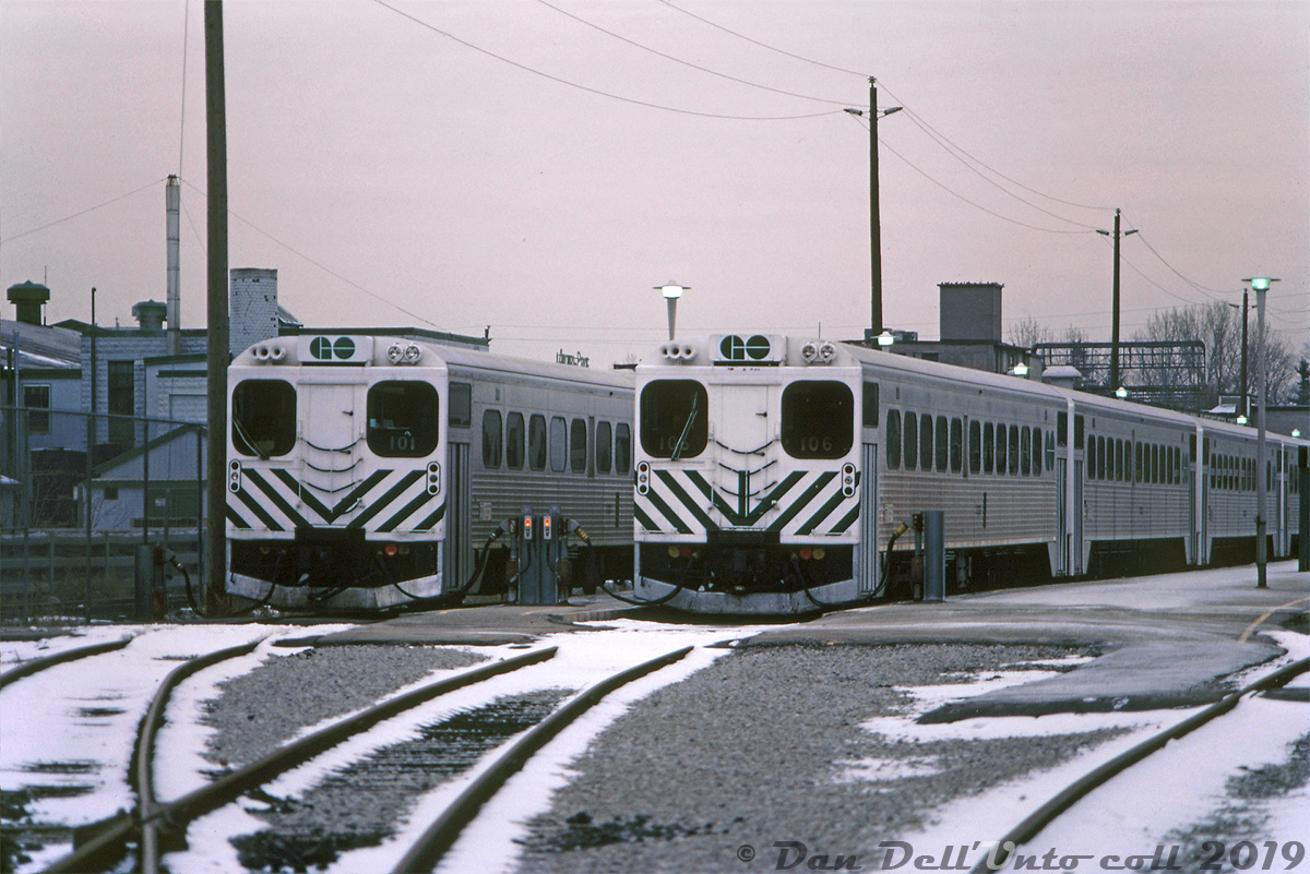 A gloomy winter Saturday at the VIA-GO Georgetown Station finds GO Transit single-level Hawker Siddeley cab cars 101 and 106 sitting on the head-end of their consists, plugged in to the wayside power outlets (that provide trains with power and heating while on layover) in the Georgetown commuter compound. Since it's the weekend, the two won't see any use until rush-hour commuters swarm the platforms on Monday morning.   The Hawker Siddeley Canada single-levels were the original equipment designed for and purchased by GO Transit for their initial startup in the mid-60's. After retirement from GO in the 90's, 101 & 106 (along with the bulk of the fleet) would go on to second careers in Montreal commuter service as AMT 202 and AMT 106 respectively, earning the nickname "GO Karts". AMT retired them in 2010, but sister car 104 would be repatriated by GO Transit in 2017 for its 50th anniversary, restored and donated to the TRHA for display at their museum in downtown Toronto.  Bill McArthur photo, Dan Dell'Unto collection slide.