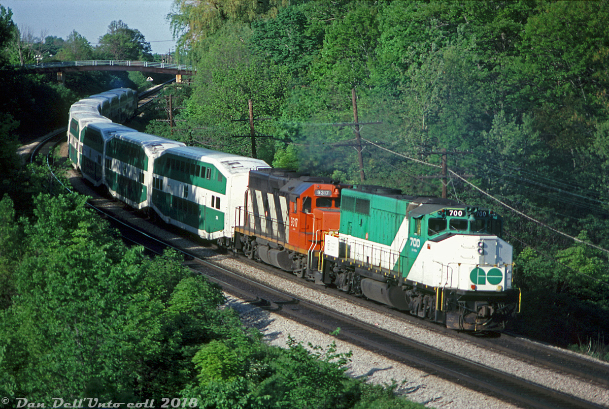 There's lots of photos of GO power running on CN and CP in freight service, but what about the opposite - CN power in GO service?

In the 1970's CN had two of their GP40's, 4016 and 4017 (later renumbered 9316 & 9317 in 1981) equipped with high-speed 89mph gearing for CN and later VIA passenger service in the southern Ontario corridor, pulling both conventional steam-heated and Tempo consists (usually with an SGU car or HEP-equipped baggage) and often mixed in with the usual passenger pool power out of Spadina roundhouse. They did however see the occasional fling in GO service: they operated for a time in the early 1970's with CN SGU cars and leased Ontario Northland coaches working in GO service on the Lakeshore corridor.

The Spring/Summer of 1982 was another time when the CN GP40 duo regularly showed up in GO Transit service, usually doubleheading behind a 700-series GP40-2W on a Lakeshore line train. Here we see GO 700 and CN 9317 teamed up pushing a consist from Hamilton, trailing 10 bilevels and an APCU heading eastbound through Bayview on the CN Oakville Sub. Photos suggest 9316, 9317 and also 9312 saw use on GO trains during this time (the rest of the 9300's were never regeared and never saw regular passenger train use. It's also questionable if 9312 was regeared for GO, or just pressed into service as-is. Anyone? Bueller? Bueller?).

The aging CN 9300's would run out their careers in freight service in the 1990's and get sold off, but not before being joined in freight service by GO's entire fleet of GP40-2W's (minus 703), sold to CN in 1991 and renumbered as high 9600's. They also initially keeping their own high-speed gearing as well.

Bill McArthur photo, Dan Dell'Unto collection scan.