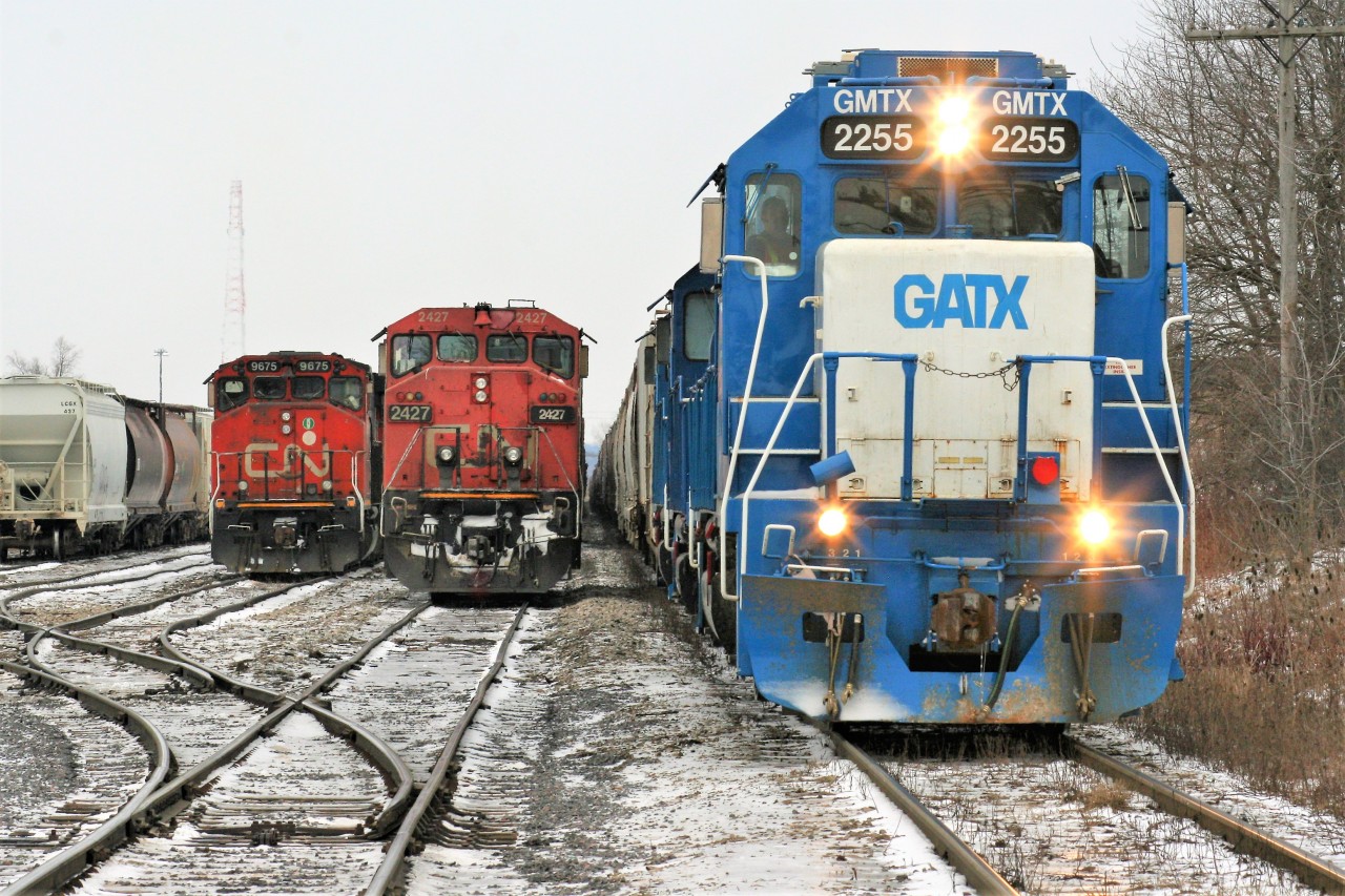During the night of February 10, CN A431 with 9675 and 9482 had a long and heavy train when it departed MacMillan yard in Toronto. Once on the Guelph Subdivision, the Niagara Escarpment grade proved too powerful for the two four-axle units. The train retreated back to (Silver) Georgetown and set-off the majority of its Stratford cars before trying another run at the grade. Eventually the units made it over and then go on to set-off 39 cars in Guelph before finally arriving in Kitchener after sunrise. The train then tied-down in Kitchener and CN would order an X431 to lift the cars left on the Halton Subdivision by A431 and bring them the remaining distance to Kitchener. Here pictured in the Kitchener yard, CN train L568 with a trio of GMTX units waits on the mainline while A431’s power from the night before looks on along with X431 and 2427.
