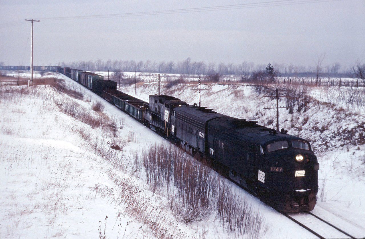 Toronto-Buffalo (Frontier Yard) train TF-2 struggles up the grade into Vinemount behind Penn Central F7As 1747, 1729 and GP9B 3829. Normally an overnight train, this morning it is quite late--likely due to a combination of winter weather and less-than-reliable power.