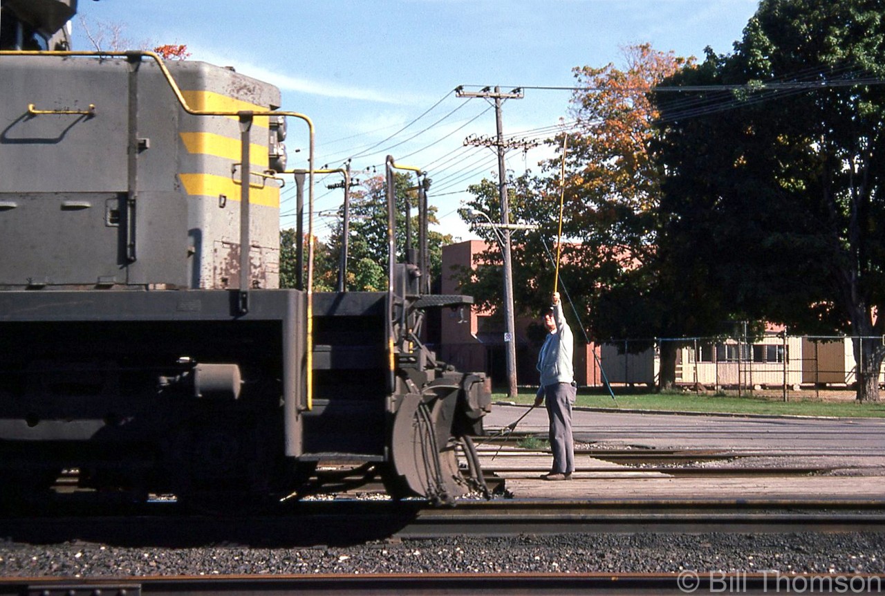 The operator at Woodstock has his train order hoop held at the ready for the head-end crew of a westbound CP freight (lead by former QNS&L SD40 204) to grab on the fly, as they cross Ingersoll Ave. on the Galt Sub. A second train order hoop in the other hand is all set for the tail-end crew to pick up when the van passes by.