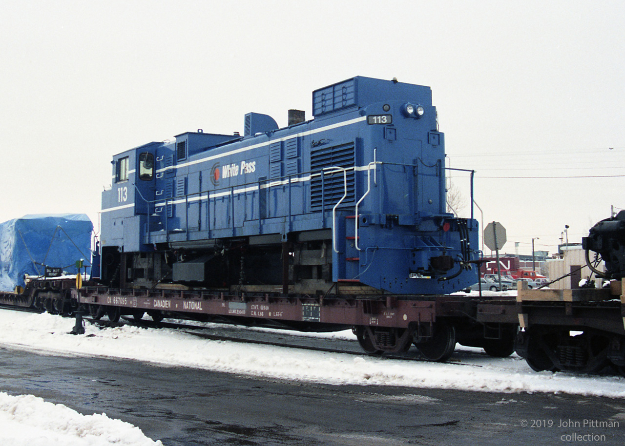 Three foot gauge White Pass & Yukon Route Railway (Skagway to Whitehorse) placed an order for 4 new road switcher locomotives with Bombardier in the early 1980's.  Units 111-114 were completed in July 1982, painted in WP&YR's new blue colour scheme. Mechanically they were quite similar to WP&YR's previous MLW / ALCo road switchers, other than the safety cab (Spec DL-535E, A1A-A1A trucks, Alco 6-251D diesel, 1200 HP).  
Unfortunately WP&YR fell on such hard times by mid 1982 (mining downturn, competition from the new parallel Klondike Highway) that they were forced to suspend operations and mothball the railway; they could not accept their new locomotives. Due to limited demand for three foot gauge locomotives, the units were stored in Quebec for many years until sold.  In 1991 units 112 and 113 were purchased by the US Gypsum Company for their 3 foot gauge railway at Plaster City, California. 
I believe that this picture shows unit 113 in transit to US Gypsum in the winter of 1991. The A1A-A1A trucks are on a flatcar behind it. 113's US Gypsum career was short, it was retired after an accident - apparently USG acquired unit 111 to replace it in 1993. Units 111 and 112 retain their WP&YR numbers, and stayed blue until 2017.  
Resurrected as a tourist operation, WP&YR acquired unit 114 in 1995.  I encountered WPYR 114 in July 2018, shutdown outside WP&YR's Skagway Alaska shops - it is their only locomotive still in the blue scheme.