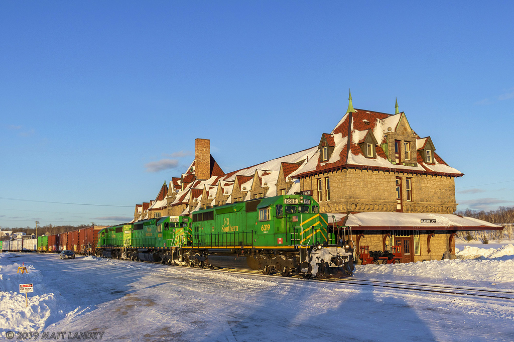 Near Sunset, NBSR train 907 passes by the famous railway station at McAdam, New Brunswick.