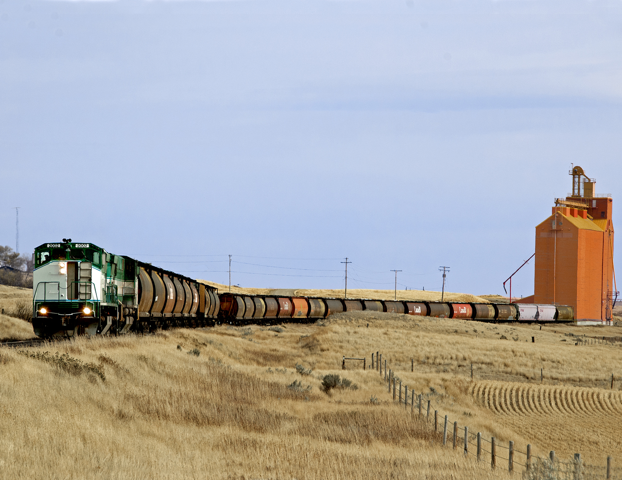 Westbound grain potter from Assiniboia to Eastend Sask. with M420's in Saskatchewan provincial colours makes a spot of empties to the Pioneer elevator at Admiral