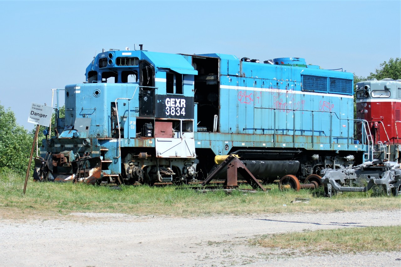 On a hot summer afternoon, the shell of retired Goderich-Exeter Railway (GEXR) GP35m 3834 and GP9 901 bask in the sun beside the former CN Goderich, Ontario station. Even in their dilapidated state, the pair are still earning their keep on GEXR, by providing usable parts to keep the rest of the GEXR four-axle motive power operating daily and earning their keep. Both units would eventually be scrapped at Goderich along with several other parts locomotives in the years that followed.