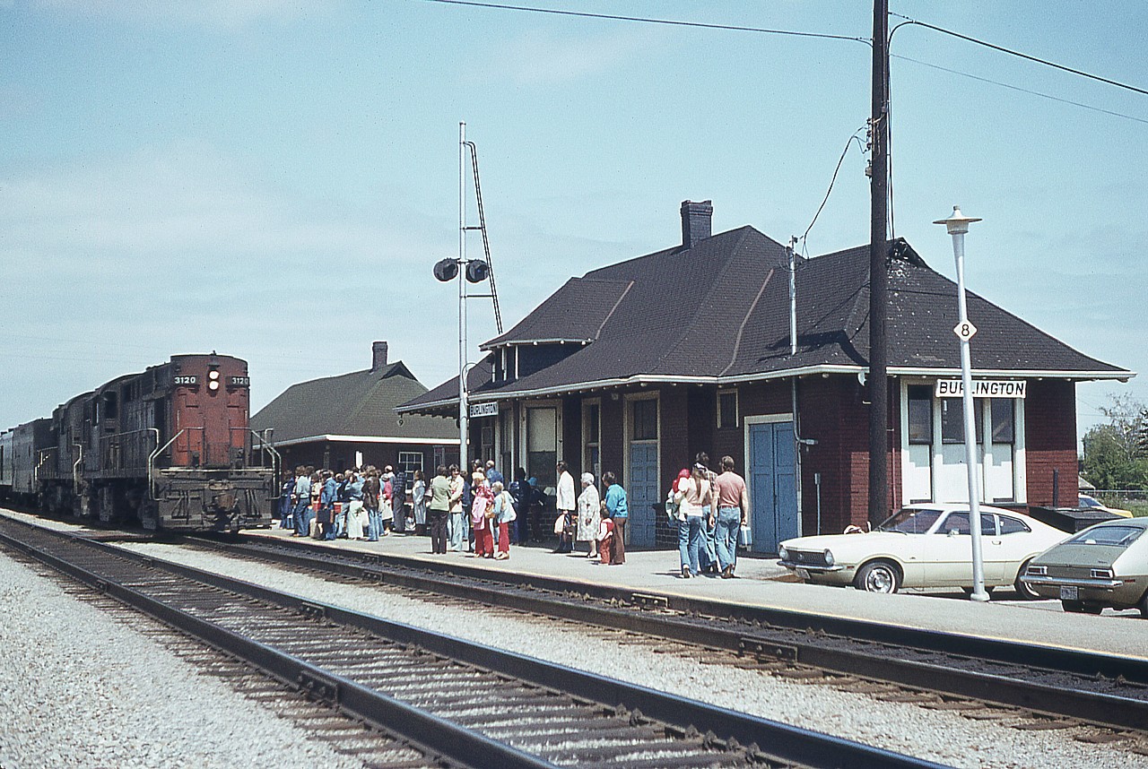 I'm disappointed my notes went a.w.o.l.on this image.  Anyway, CN 3120 leads westbound to a stop at Burlington West on a late afternoon in June. The crowds of passengers (yes, it really was that busy) makes me think this is the 'dinner hour' train as I used to call it; which would make it #75 around 1700 hrs. Burlington West was such a busy place back then. Not only with people but the pigeons have decorated the roof quite a bit as well.
Interesting to note a steam genny in old CN paint behind the RS-18s, and on the right, an classic example of a road-lemon back then, a Ford Pinto. Unforgettable, those things..........