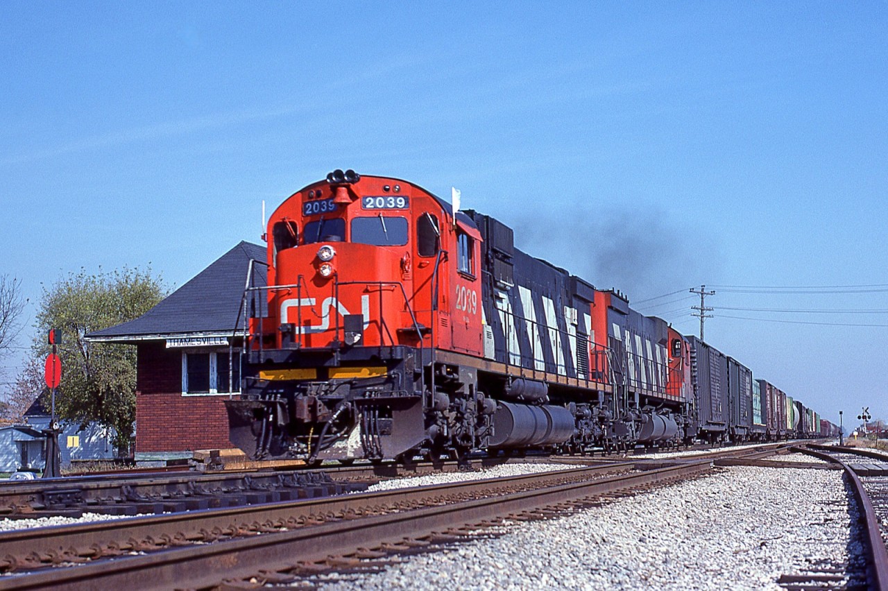 Getting 'er done, Windsor-bound CN Extra 2039 West pounds the rails as it blows by the old Thamesville station at mile 46.5 on the CN's Chatham Sub. Trailing unit is the CN 2326.