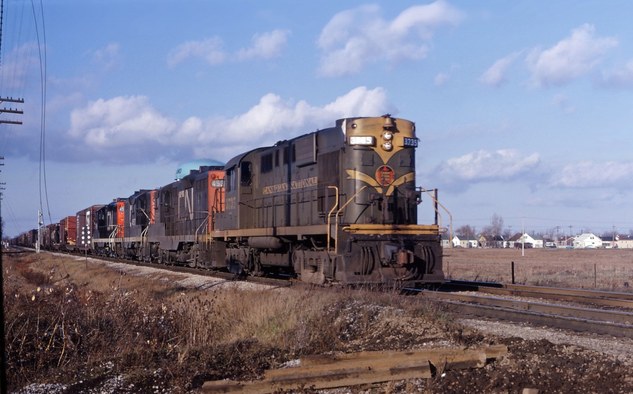 On a snow-less day in January 1967, a CN freight heads through Welland on its way to Fort Erie. Between deliveries of new locomotives and repaints, the "1961 image" is now very common, although you could still occasionally catch units in the "old colours"...trains with three or four 4-axle units were quite common at that time, often intermixing RS18s with GP9s as well as GP40s and C-424s. (The SD40/C630 era had not yet arrived.)